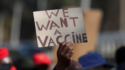 A protester holds a sign that reads "we want a vaccine" in South Africa
