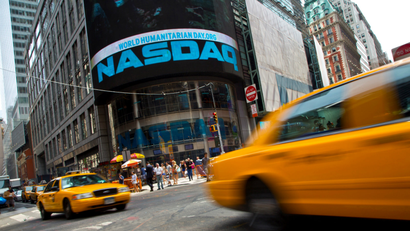 A photograph of Taxi cabs drive past the Nasdaq MarketSite in New York's Times Square