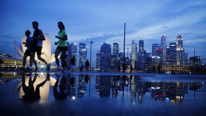 Joggers run past as the skyline of Singapore's financial district is seen in the background April 21, 2014. REUTERS/Edgar Su (SINGAPORE - Tags: CITYSCAPE SPORT ATHLETICS BUSINESS SOCIETY) - RTR3M2JB