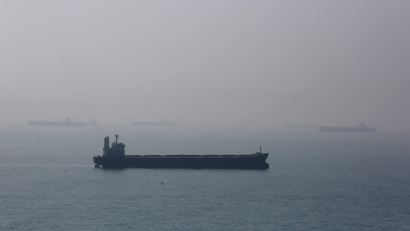 A ship sails past bulk carriers lying idle off the coast of the southern tip of Hong Kong