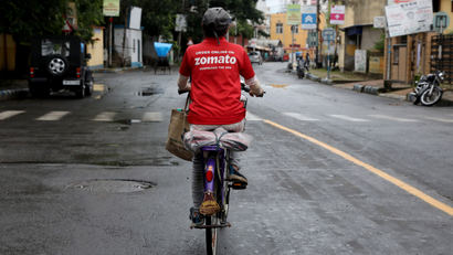 A delivery worker of Zomato rides her bicycle along a road in Kolkata