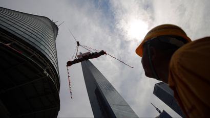 A worker looks a piece of steel lifted by a crane during the topping out ceremony at the Shanghai Tower, which is undergoing construction, at the financial district of Pudong in Shanghai August 3, 2013. The 632 metres (2,073 ft) high Shanghai Tower, which is scheduled to finish construction by the end of 2014, will be the tallest skyscraper in China and the second tallest in the world. REUTERS/Carlos Barria
