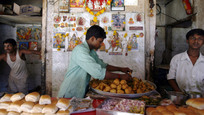 Vendor arranges vada Pav, a spicy potato ball fried in batter and served in a bun, at a street-side snack stall in Mumba