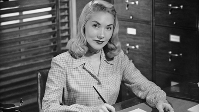Black-and-white photo of a woman in the 1950s working in an office