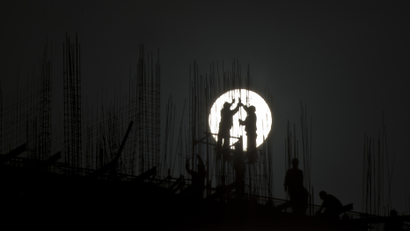 Construction workers install scaffolding on the top of a building during sunset in Shanghai November 11, 2012. China announced on Saturday that it is effectively turning the corner on the economy and likely to meet its growth target for the year, more good news for Communist Party policy makers meeting in Beijing to anoint new leaders for the next decade. REUTERS/Aly Song
