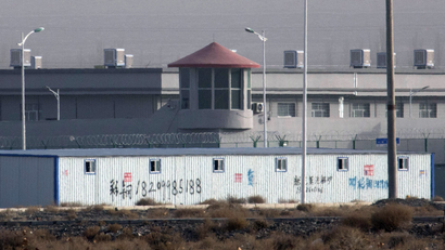 A guard tower and barbed wire fences are seen around a facility in Xinjiang