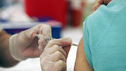 A person administering a flu shot to someone's arm.