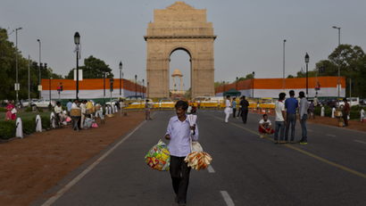 An Indian vendor sells snacks in front of the landmark India Gate war memorial, decorated in the colors of the Indian national flag, on the eve of the country’s Independence Day in New Delhi, India, Thursday, Aug. 14, 2014. India celebrates its 1947 independence from British colonial rule on Aug. 15.