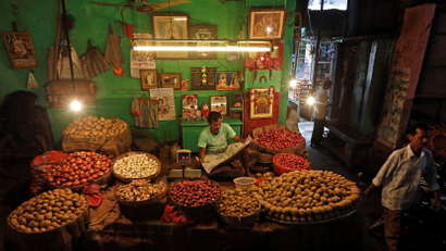 A vendor reads a newspaper at his vegetable shop as he waits for customers in Kolkata
