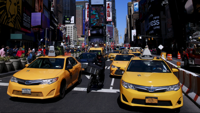 Yellow taxi cabs drive through Times Square in New York City.