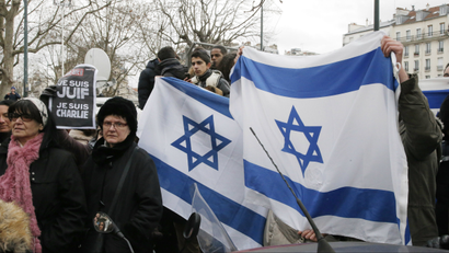 People wave Israeli flags after Israeli Prime Minister Benjamin Netanyahu's visit to the kosher market where four hostages were killed, in Paris, France, Monday, Jan. 12, 2015.