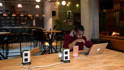 A resident or 'member' works at a computer in a shared space at The Collective co-living building in west London