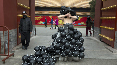 Performance artiste Kong Ning dresses in a gown depicting black granule during a street performance to raise awareness of air pollution in Beijing on Sunday, March 4, 2018. (AP Photo/Ng Han Guan)