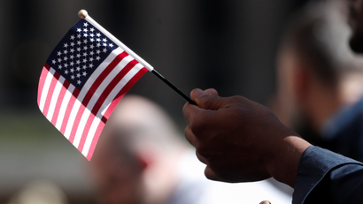 A citizenship candidate holds a flag during the U.S. Citizenship and Immigration Services (USCIS) naturalization ceremony at Rockefeller Plaza in New York City