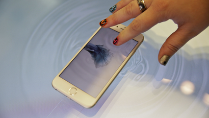 A woman press an Apple iPhone 6s on a 3D touch table at the Apple store Friday, Nov. 13, 2015, in San Francisco. The table allows people to get a better sense of the touch capabilities of the phone. (AP Photo/Eric Risberg)