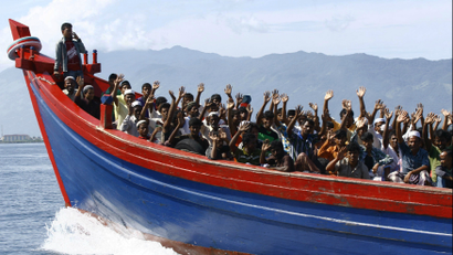 Ethnic Rohingya refugees from Myanmar wave as they are transported by a wooden boat to a temporary shelter in Krueng Raya in Aceh Besar April 8, 2013.