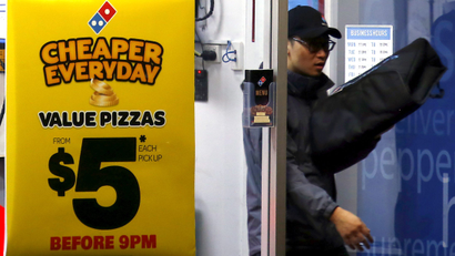 A worker carries a pizza for delivery as he exits a Domino's pizza store in Sydney, Australia
