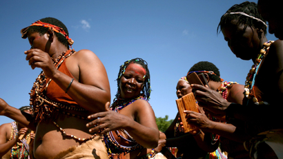 Women dressed in beaded animal skins perform celebratory dances.
