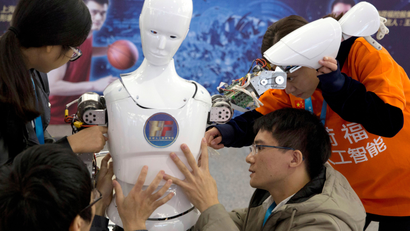 In this Oct. 21, 2016, file photo, Chinese students work on the Ares, a humanoid bipedal robot designed by them with fundings from a Shanghai investment company, displayed during the World Robot Conference in Beijing. China's government announced Thursday, July 21, 2017, a goal of transforming the country into a global leader in artificial intelligence in just over a decade, putting additional political support behind growing investment by Chinese companies in developing self-driving cars and other advances. (AP Photo/Ng Han Guan, File)