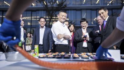Alibaba Groups executive chairman Jack Ma (C) looks on as a chef prepares to slice salmon at a display area for fresh food ingredient vendors, who recently signed a cooperation agreement with Alibaba's Tmall, after the launch event of Tmall 11.11 Global Shopping Festival, at the company's headquarters in Hangzhou, Zhejiang province, China, October 13, 2015. REUTERS/Stringer CHINA OUT. NO COMMERCIAL OR EDITORIAL SALES IN CHINA. - RTS49DX