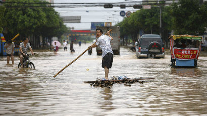 Resident paddling a homemade raft on a flooded street