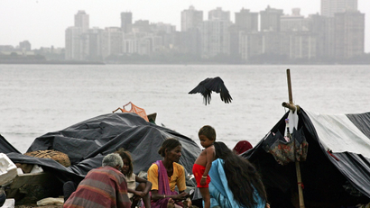 A homeless Indian family sits on a beach in Bombay August 4, 2005. [India's share index rose to its ..