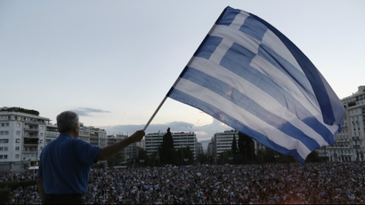 A demonstrator waves a Greek flag as he stands on the parliament demanding that Greece remains in the Eurozone, outside the parliament in Athens, Greece, 18 June 2015.