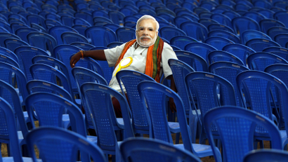 A supporter of Modi, prime ministerial candidate for BJP, wears a mask depicting Modi as he sits before the start of an election campaign rally in the southern Indian city of Chennai