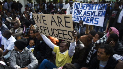 An African migrant holds up a sign as he sits with compatriots on the third day of protests against Israel's detention policy toward migrants it sees as illegal job-seekers, in Tel Aviv's Levinsky park January 7, 2014.