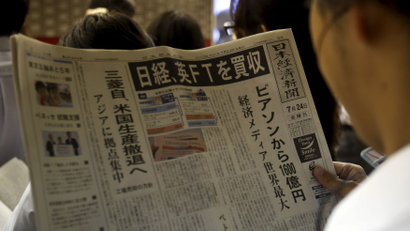 A man reads the front page of Japan's Nikkei newspaper reporting Japanese media group Nikkei's acquisition of the Financial Times from Britain's Pearson at a train station in Tokyo