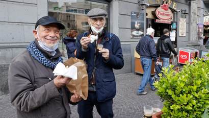 Two men eat outside a coffee shop in Naples. One smiles at the camera.