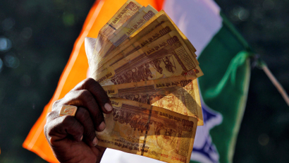 A man displays 500 Indian rupee notes