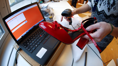 A fitting model enters data in a laptop after she checks out sizes for a shoe which goes on sale at the online shop of fashion retailer Zalando