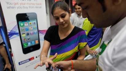 A salesperson, left, at a mobile phone shop helps a customer with the working of the Apple iPhone 4 in New Delhi, India, Friday, May 27, 2011. The Apple iPhone was launched in India Friday and is priced at 34,500 rupees ($747) for the 16GB and 40,900 rupees ($909) for the 32GB. (AP Photo/Manish Swarup)