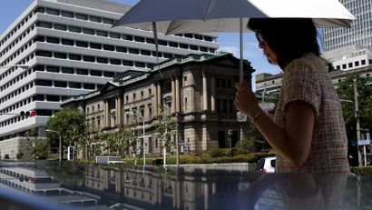 A woman holding an umbrella walks in front of the Bank of Japan headquarters in Tokyo