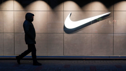 A man walks past a building with the white Nike swoosh logo.