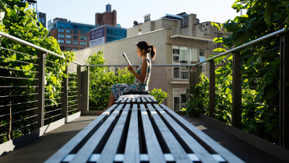 A woman uses the late afternoon sun to read while sitting on the High Line park in New York