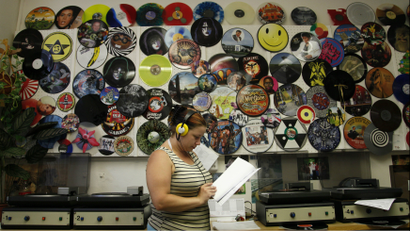 A woman listening to records in a record store.