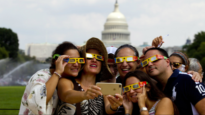 A family takes a selfie wearing a safety glasses to watch phases of solar eclipse, at the National Mall in Washington, Monday, Aug. 21, 2017.