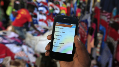A man holds up his mobile phone showing a M-Pesa mobile money transaction page in Nairobi.