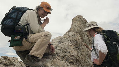 Two female paleontologists are examining rock remains.
