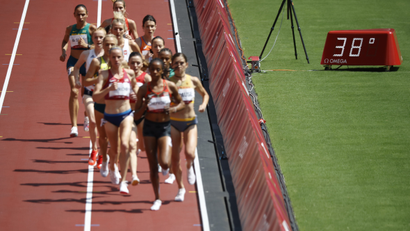 Women participate in the 3000m steeplechase beside a thermometer that lists the temperature at 38˚C (100.4˚F)