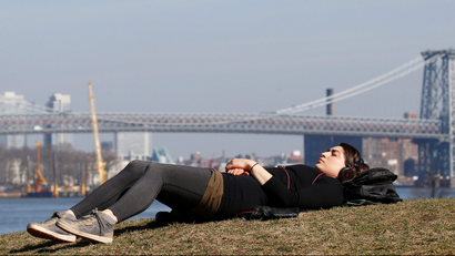A woman naps in Brooklyn Bridge Park during unseasonably warm weather in Brooklyn, New York