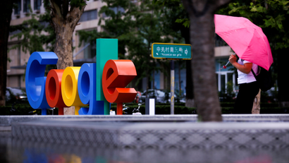 Google's logo is seen on a rainy city street.