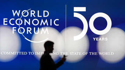 A man silhouettes in front of the logo of the World Economic Forum in Davos, Switzerland