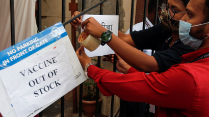 Health workers attach a notice on the shortage of COVID-19 vaccine supplies at a vaccination centre in Mumbai