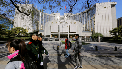 People walk past the headquarters of the People's Bank of China (PBOC), the central bank, as two paramilitary police officials patrol around it in Beijing November 20, 2013.
