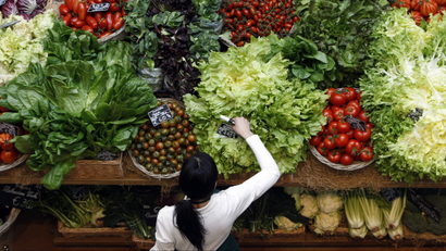 An employee arranges pricetags at a vegetables work bench during the opening day of upmarket Italian food hall chain Eataly's flagship store in downtown Milan.