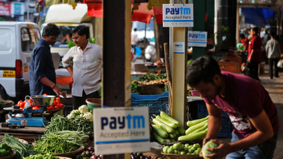 Advertisement boards of Paytm, a digital wallet company, are seen placed at stalls of roadside vegetable vendors as they wait for customers in Mumbai