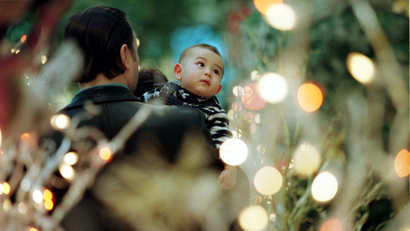 A baby looks at Christmas tree lights.